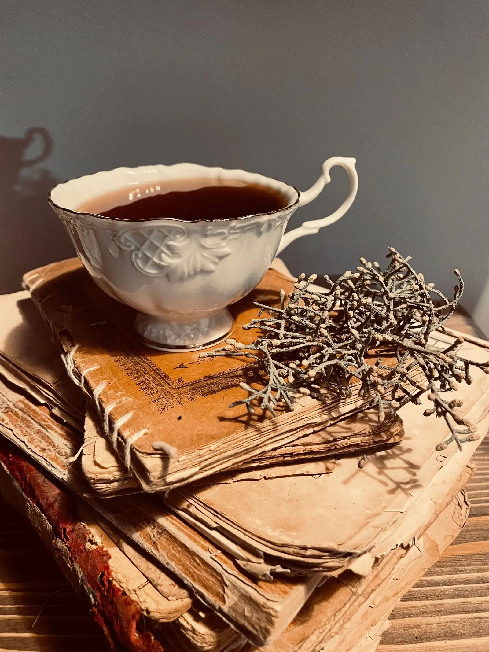 Tasse en porcelaine décorée posée sur une pile de livres anciens